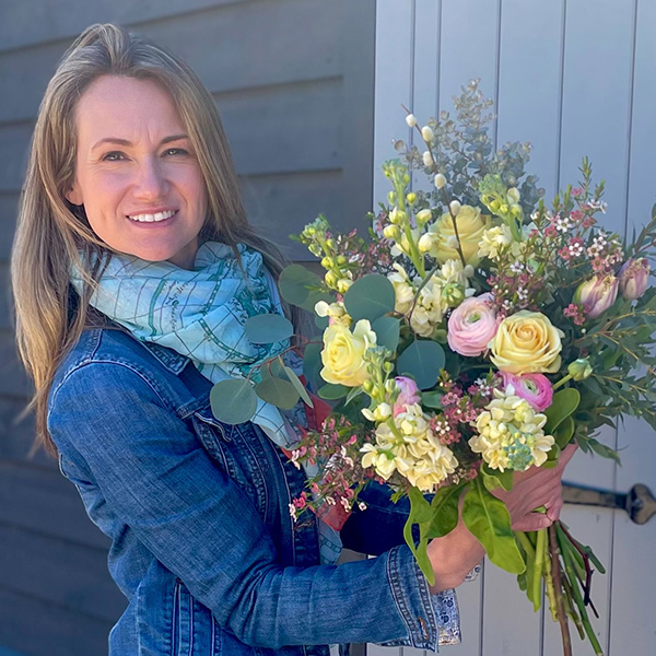 Photo of Sarah, owner of Bluebell Lane floristry, holding a bouquet of flowers.